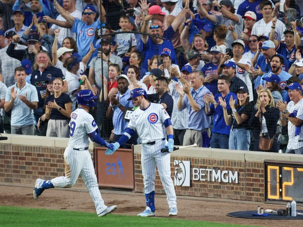Cubs Michael Busch, left, celebrates with outfielder Ian Happ after...