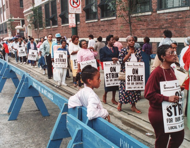 On Sept. 8, 1987, third-grader Latoya Shaw, 8, watches as her mother, a teacher's aide, walks in the picket line at the Chicago school board office. It was the first day of a strike that would last a record 19 days. (Carl Hugare/Chicago Tribune)