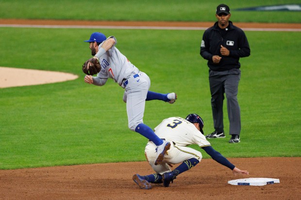 Milwaukee Brewers shortstop Joey Ortiz (3) slides under Chicago Cubs...