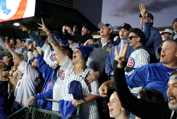 Chicago Cubs fans sing during the seventh inning stretch of...