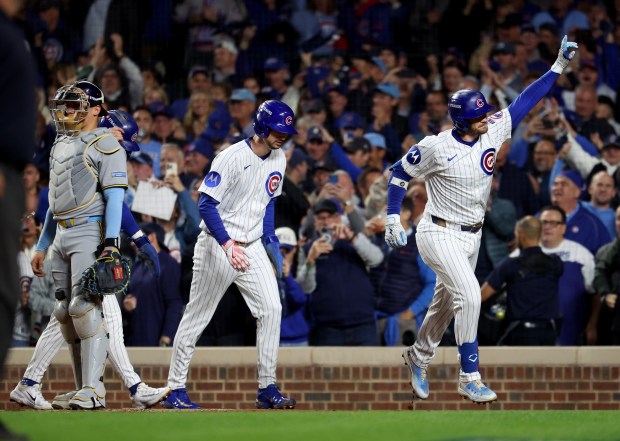 Cubs left fielder Ian Happ celebrates after hitting a three-run...