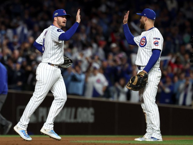 Chicago Cubs left fielder Ian Happ, left, and first baseman...