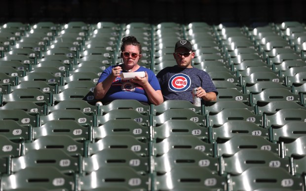 Two Chicago Cubs fans relax in their seats before the...