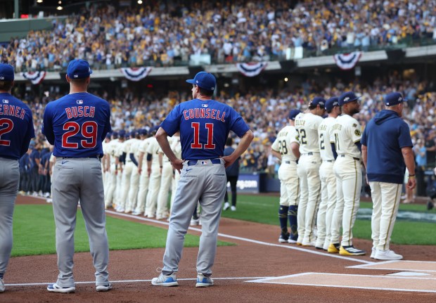 Chicago Cubs first baseman Michael Busch (29) and manager Craig Counsell (11) stand by as the Milwaukee Brewers are introduced before the start of the NL Division Series Game 1 at American Family Field in Milwaukee on Oct. 4, 2025. (Chris Sweda/Chicago Tribune)