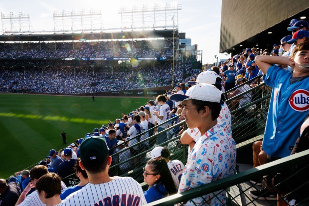 Fans stand in the bleachers while the Cubs play the...