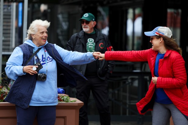 Chicago Cubs fan Lori Walker, right, of Birmingham, Ala., says goodbye to Sam Bernero, who has a following on social media for photographing Chicago Cubs player arrivals, outside of Wrigley Field on Wednesday, May 28, 2025. Walker's son Carson knew of Bernero from following her on social media (Eileen T. Meslar/Chicago Tribune)