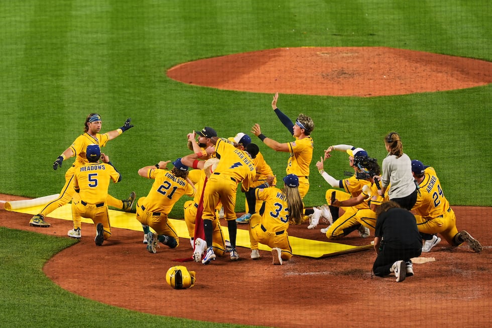 Savannah Bananas' Bill Leroy, left, does the splits over a yellow carpet while greeted by...