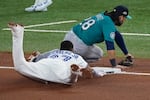 Seattle Mariners' Eugenio Suárez can't catch a throwing error by catcher Cal Raleigh as Toronto Blue Jays' Vladimir Guerrero Jr. dives into third during the seventh inning in Game 6 of baseball's American League Championship Series, Sunday, Oct. 19, 2025, in Toronto.