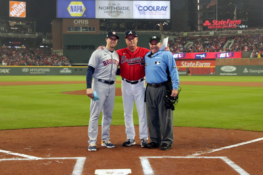 Astros hitting coach Troy Snitker #46, his father and Braves manager Brian Snitker #43 and home-plate umpire Tom Hallion #20 pose for a photo during Game 3 of the 2021 World Series.