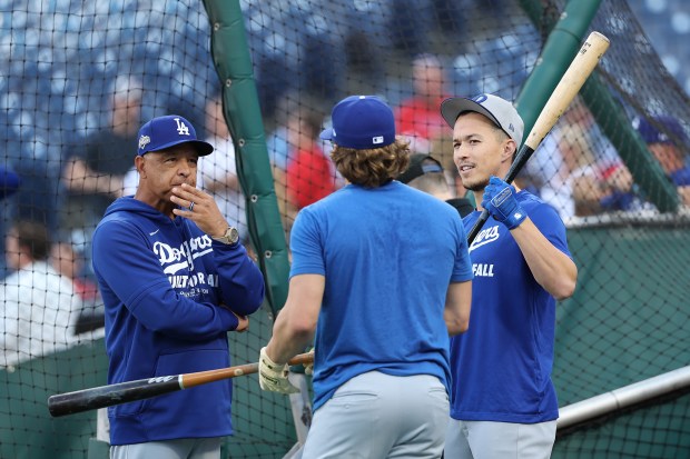 Dodgers manager Dave Roberts, left, talks with utility players Kike...
