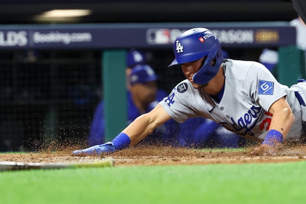 The Dodgers’ Tommy Edman slides home to score in the...