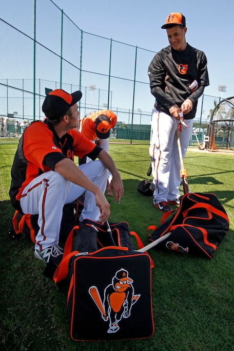 Baltimore Orioles' J.J. Hardy, left, talks with Manny Machado, right, while waiting to take batting practice during the team's first full squad workout of baseball spring training in Sarasota, Fla., Wednesday, Feb. 19, 2014.