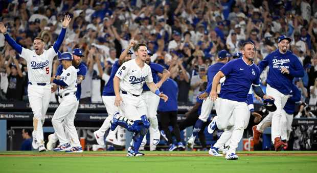 The Dodgers rush the field to celebrate their 2-1, 11-inning...