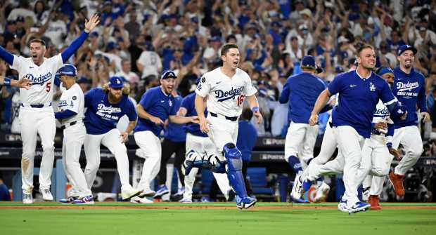 The Dodgers rush the field to celebrate their 2-1, 11-inning...