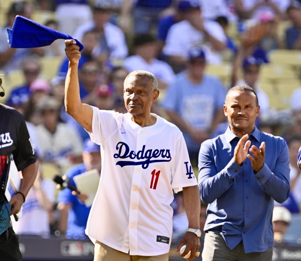 Former Dodgers player and coach Manny Mota, left, stands with...