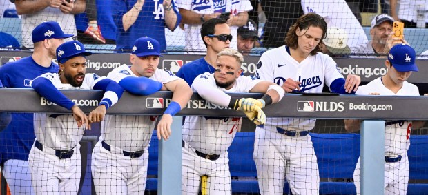 Dodgers players, including infielder Miguel Rojas, center, look on from...