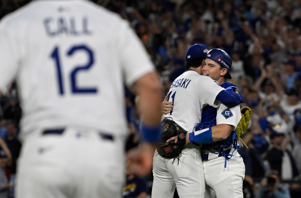Cather Will Smith #16 hugs relief pitcher Roki Sasaki #11...
