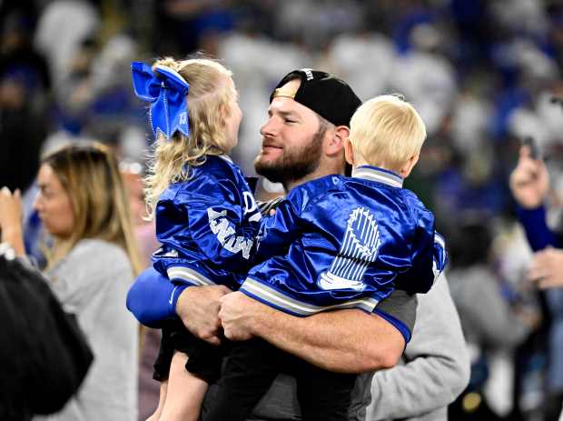 Dodgers third baseman Max Muncy hugs his children after they...