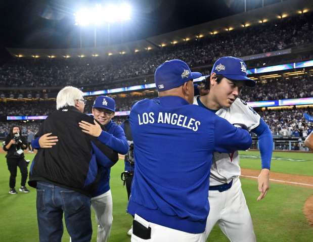 Shohei Ohtani, right, hugs manager Dave Roberts of the Los...