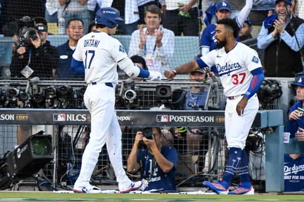 Dodgers star Shohei Ohtani, left, is greeted by teammate Teoscar...