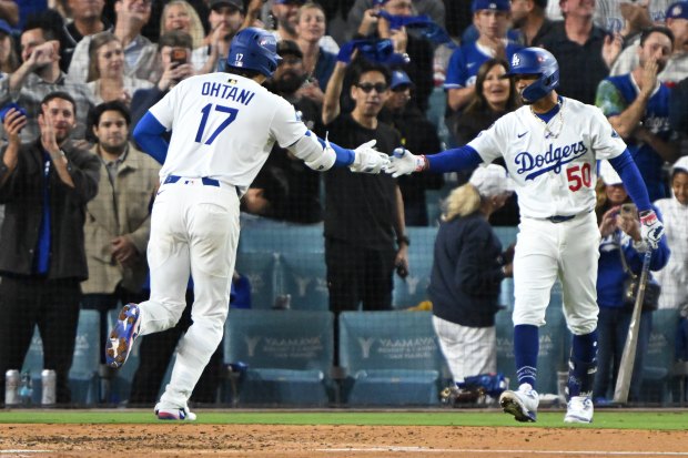 Dodgers star Shohei Ohtani, left, is congratulated by teammate Mookie...