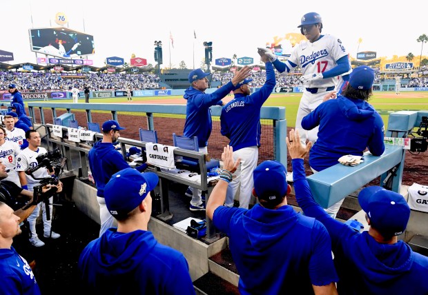 Dodgers star Shohei Ohtani (17) high-fives Manager Dave Roberts as...