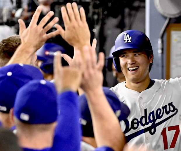 Dodgers star Shohei Ohtani celebrates in the dugout after hitting...