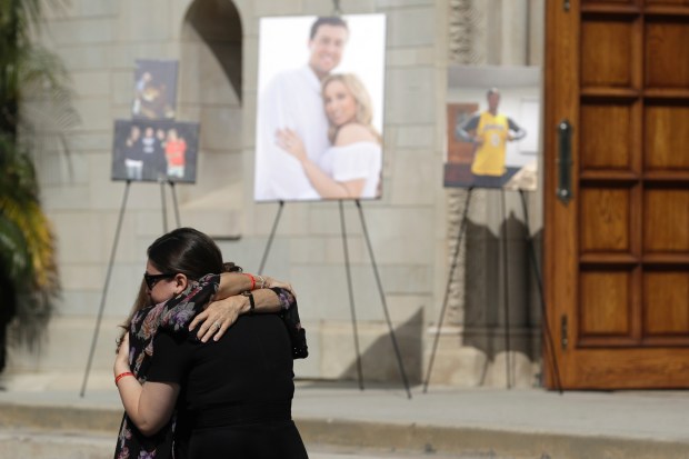 FILE – Mourners embrace during a memorial for Los Angeles...