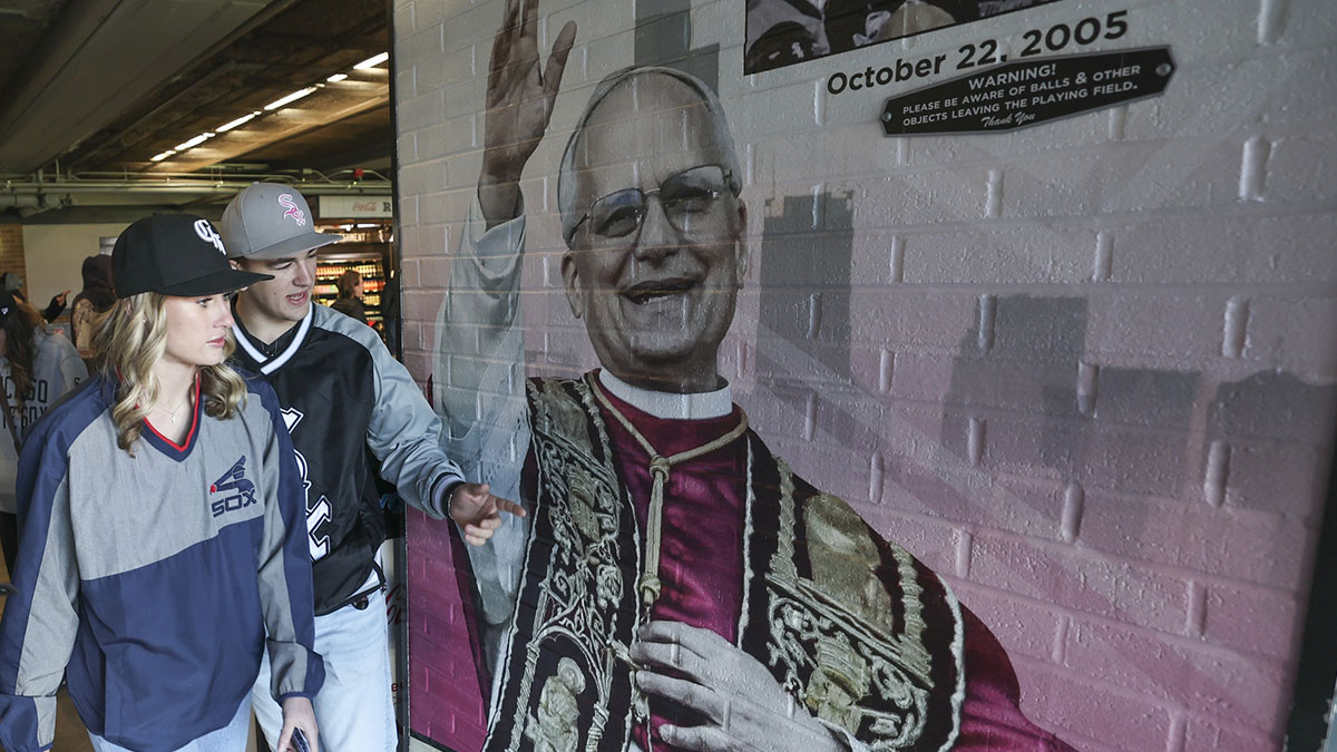 Fans walk by fandom of Pope Leo XIV with graphics before a baseball game between the Chicago White Sox and Texas Rangers at Rate Field.