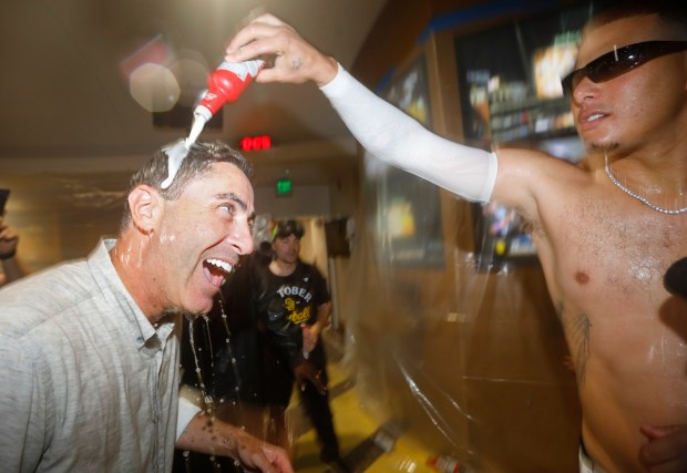 Manny Machado #13 of the San Diego Padres, right, celebrates in the clubhouse with A.J. Preller, President of Baseball Operations and General Manager after beating the Milwaukee Brewers to secure a playoff spot at Petco Park on Sept. 22, 2025 in San Diego, CA. (K.C. Alfred / The San Diego Union-Tribune)