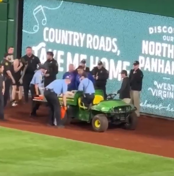 First responders attending to Kavan Markwood who fell at an MLB game, on the field by a green utility vehicle.