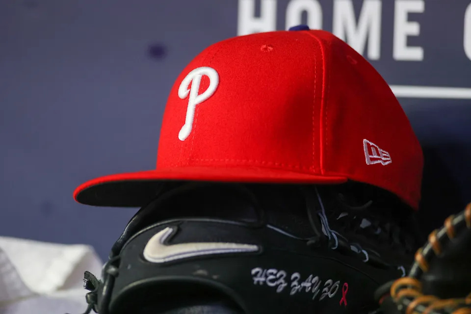 A Philadelphia Phillies hat and glove sit in the dugout.Brett Davis-Imagn Images