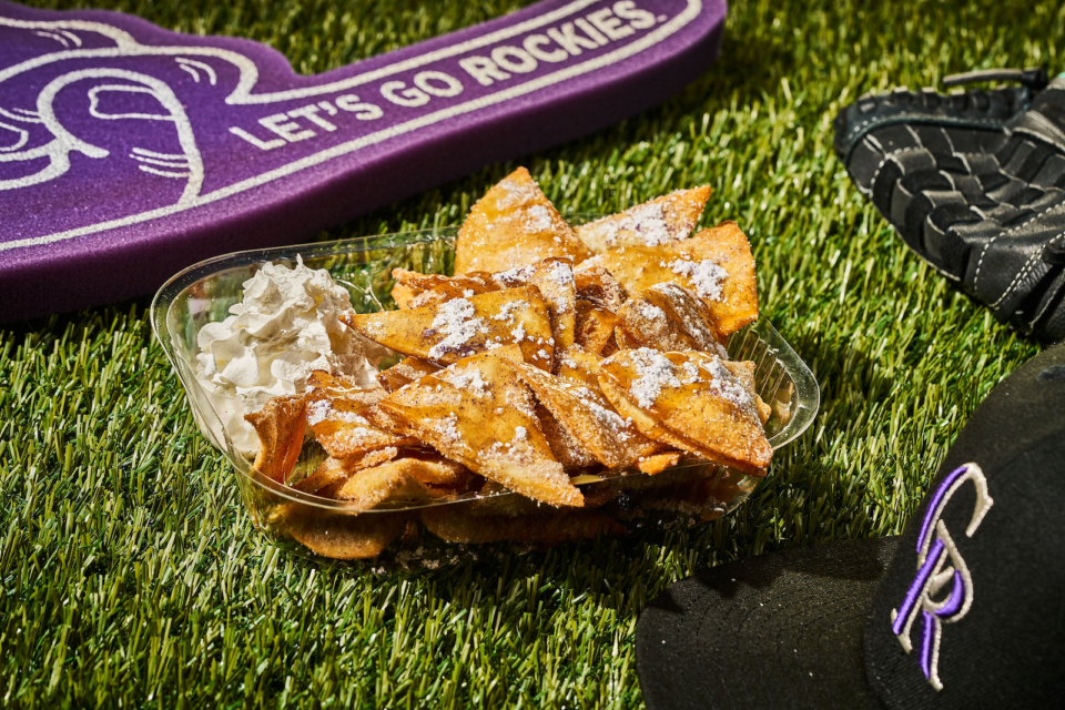 Dessert nachos with powdered sugar and caramel sauce in a basket on artificial turf with a let's-go-rockies foam finger