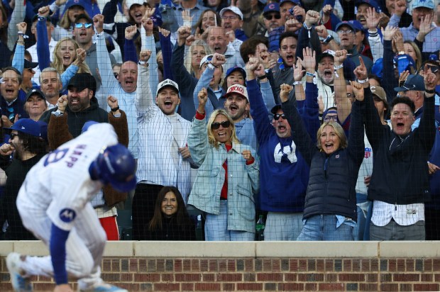 Fans celebrate as Cubs left fielder Ian Happ scores on...