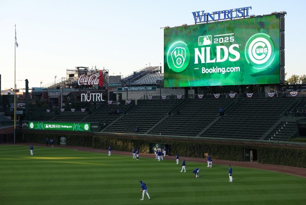 Cubs players stand in the outfield during batting practice before...