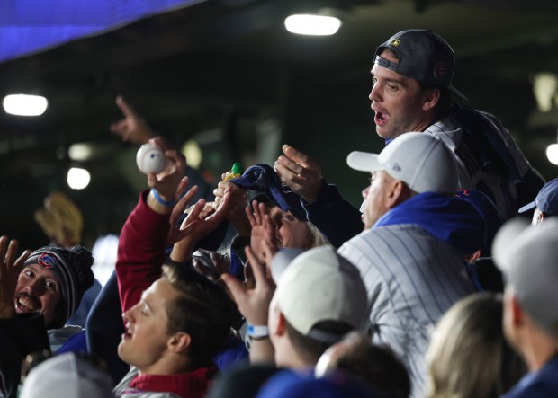 Fans in the bleachers reach for a tossed ball from the field before Game 4 of the NLCS between the Cubs and Brewers at Wrigley Field on Oct. 9, 2025, in Chicago. (John J. Kim/Chicago Tribune)
