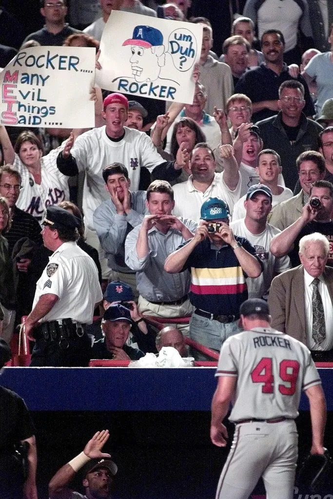 Fans jeer and hold up signs as Atlanta Braves’ pitcher John Rocker (bottom R) heads into the dugout after getting out all three New York Yankee batters he faced in the eighth inning 29 June 2000 at Shea Stadium in Flushing, NY. AFP via Getty Images