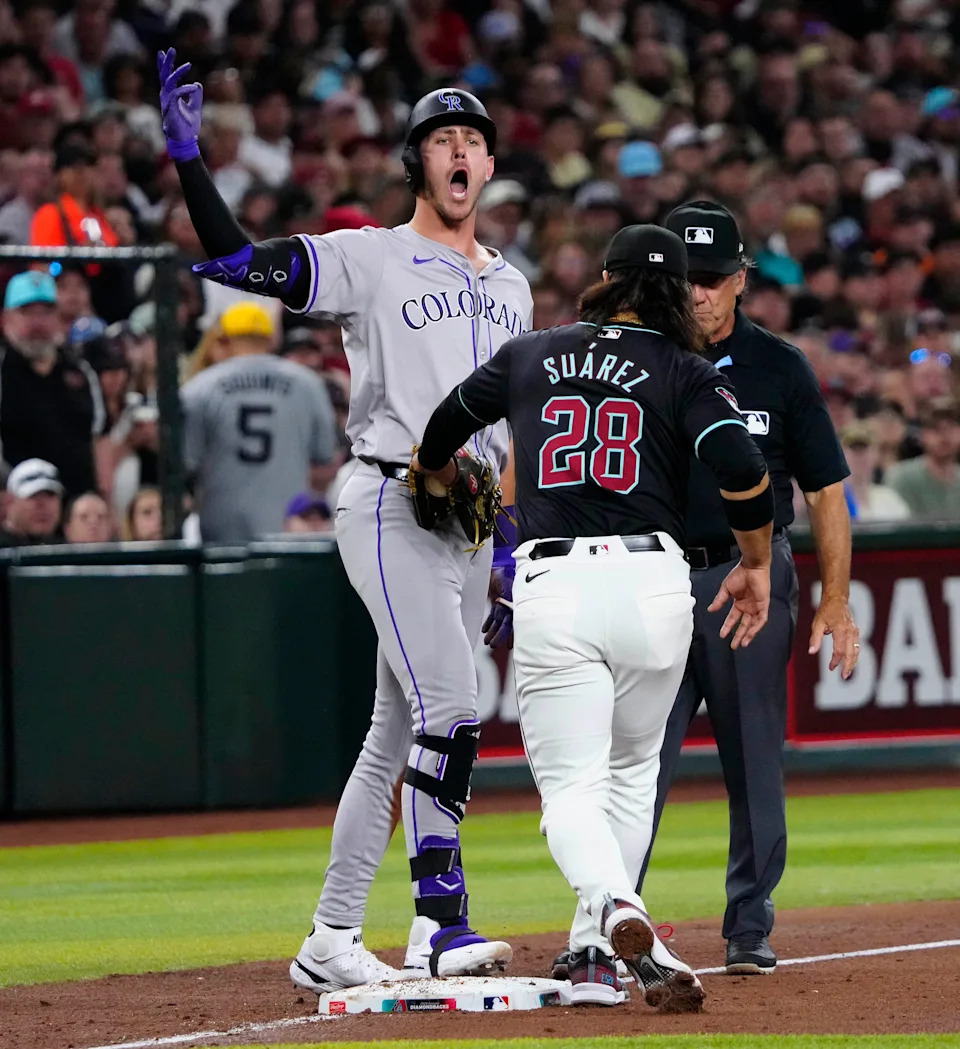 The Diamondbacks' Eugenio Suárez (28) applies a late tag as the Rockies' Nolan Jones (22) celebrates a two-run triple during a game at Chase Field.