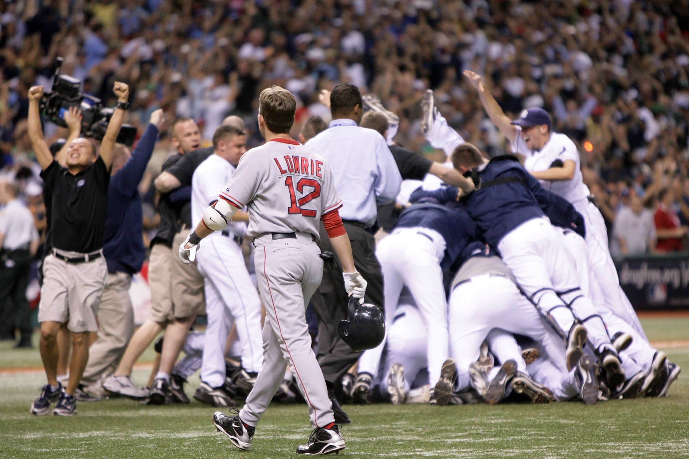 ST PETERSBURG, FL - OCTOBER 19: Jed Lowrie #12 of the Boston Red Sox walks off the field as the Tampa Bay Rays celebrate winning game seven of the American League Championship Series during the 2008 MLB playoffs on October 19, 2008 at Tropicana Field in St Petersburg, Florida. The Rays defeated the Red Sox 3-1 to win the series 4-3. (Photo by Doug Pensinger/Getty Images)