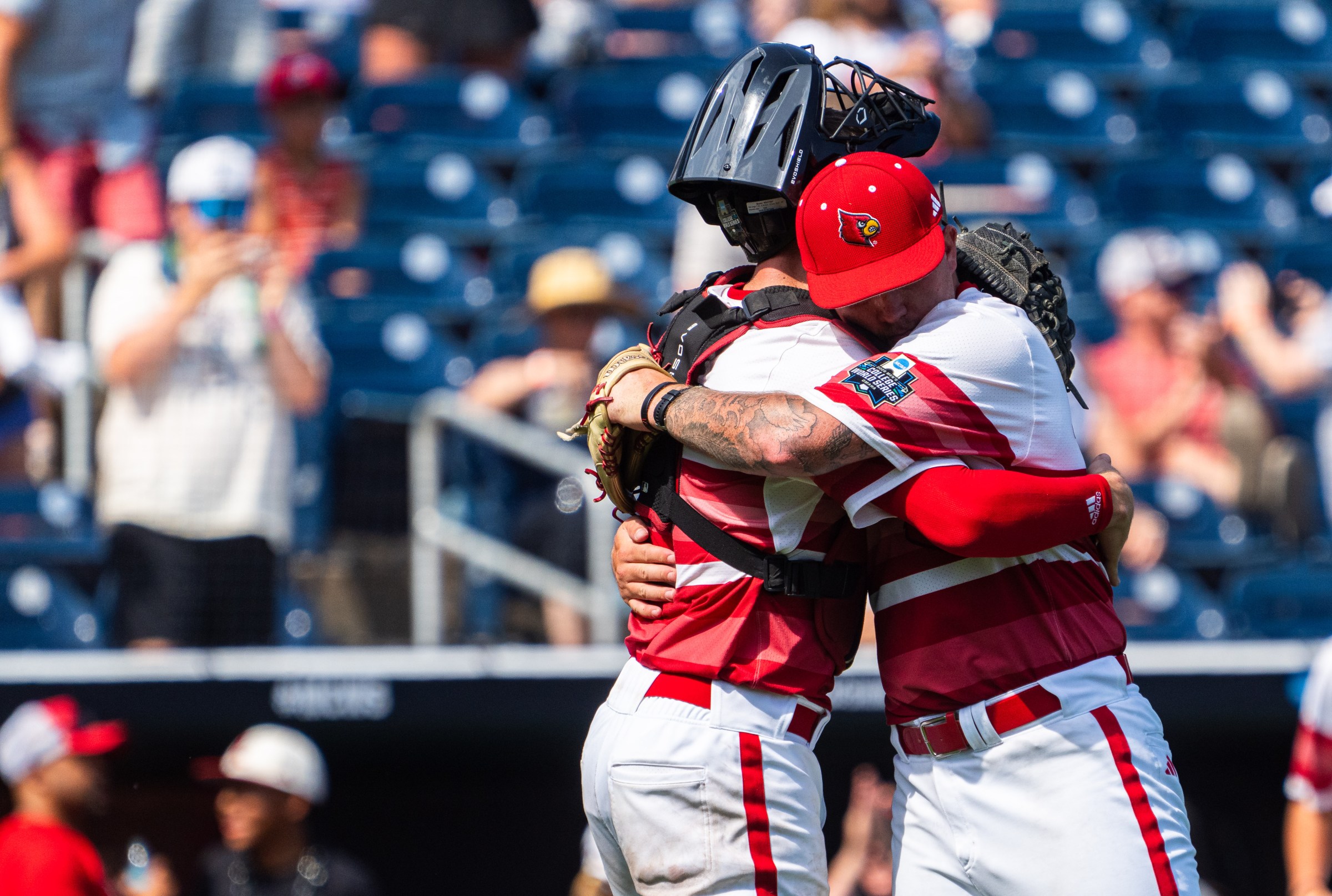 Jun 15, 2025; Omaha, Neb, USA; Louisville Cardinals pitcher Tucker Biven (22) and catcher Matt Klein (25) embrace after defeating the Arizona Wildcats at Charles Schwab Field. Mandatory Credit: Dylan Widger-Imagn Images