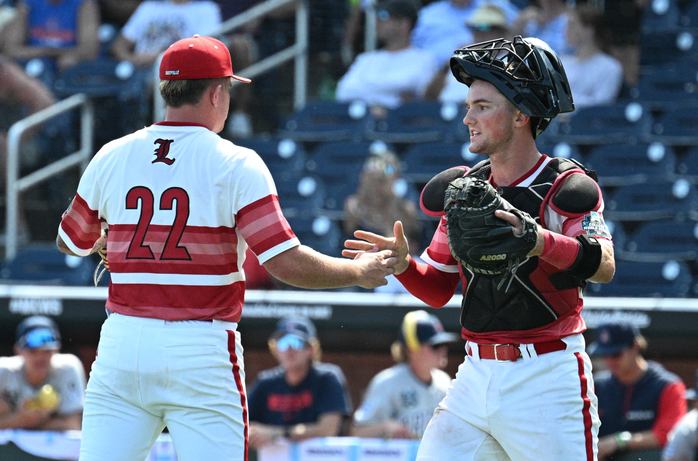 Jun 15, 2025; Omaha, Neb, USA; Louisville Cardinals pitcher Tucker Biven (22) and Louisville Cardinals catcher Matt Klein (25) celebrate the win against the Arizona Wildcats at Charles Schwab Field. Mandatory Credit: Steven Branscombe-Imagn Images