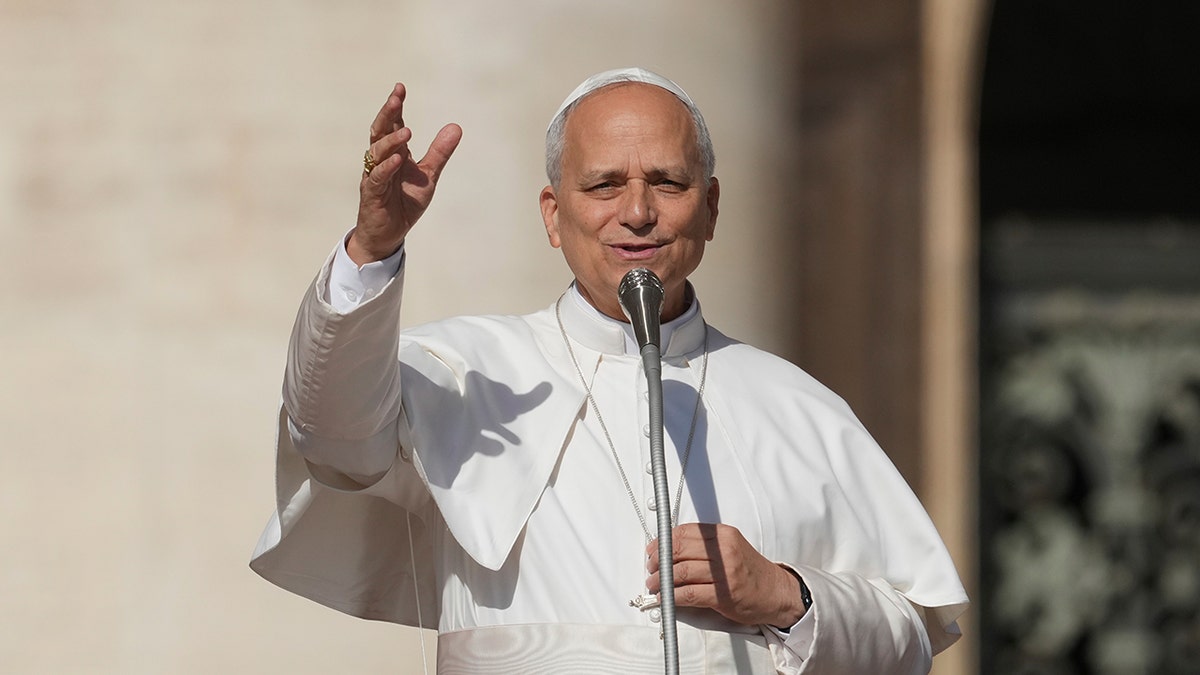 Pope Leo XIV raises hand toward crowd in St. Peter's Square.