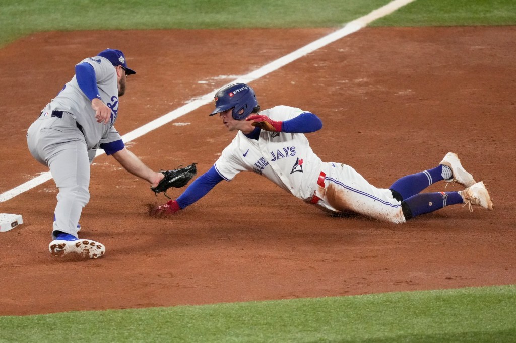 Ernie Clement of the Toronto Blue Jays is tagged out by Los Angeles Dodgers third baseman Max Muncy.