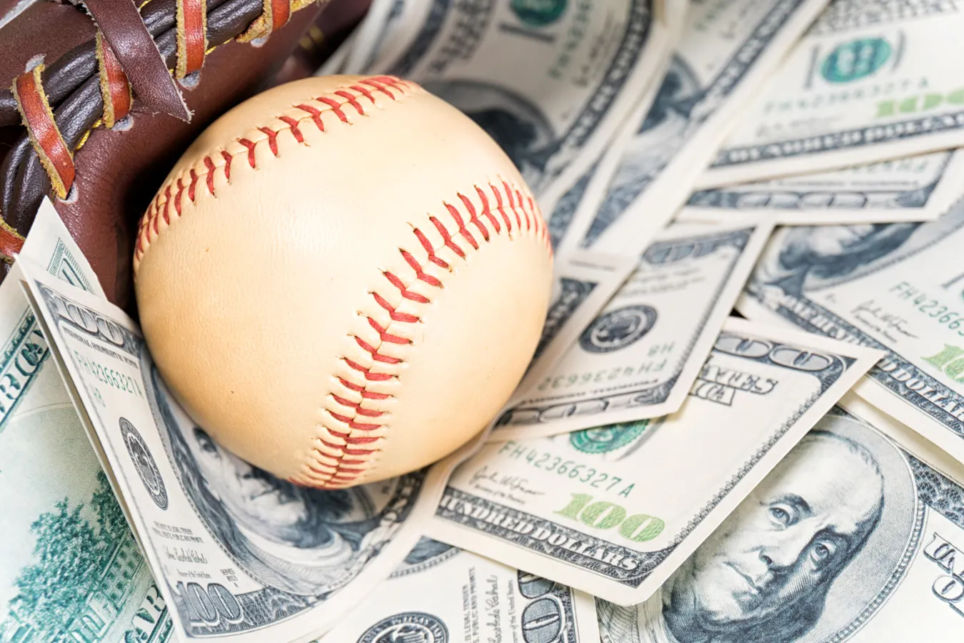 Major League Baseball sitting on a stack of cash, symbolizing player salaries and high-value contracts.