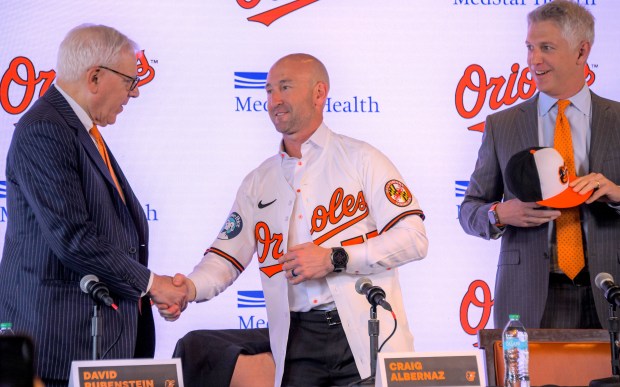 Craig Albernaz, newly hired as manager of the Baltimore Orioles, center shakes hands with David Rubenstein, control owner while Mike Elias, team president of baseball operations and general manager looks on during a press conference at Oriole Park at Camden Yards. (Karl Merton Ferron/Staff)