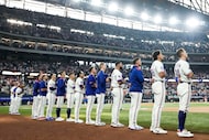Texas Rangers players stand for the the national anthem before a baseball game against the...