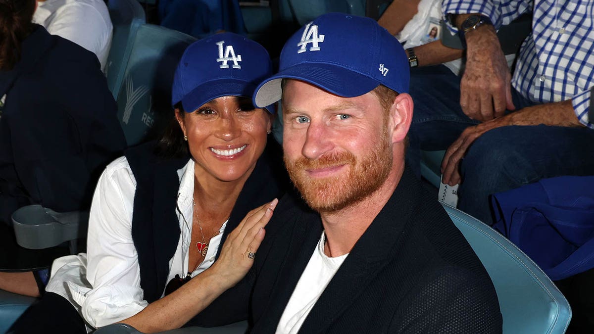 Prince Harry and Meghan Markle smile and pose at Dodgers game.