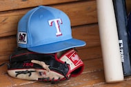 Bats, gloves and caps are seen in the Texas Rangers dugout before a spring training game...