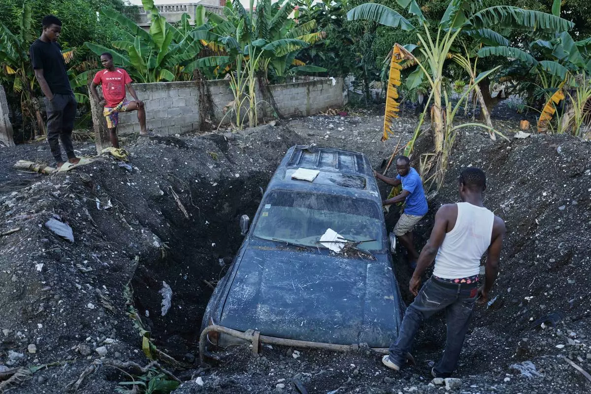 Residents work to remove a partially buried vehicle in the aftermath of Hurricane Melissa in Petit-Goave, Haiti, Thursday, Nov. 6, 2025. (AP Photo/Odelyn Joseph)