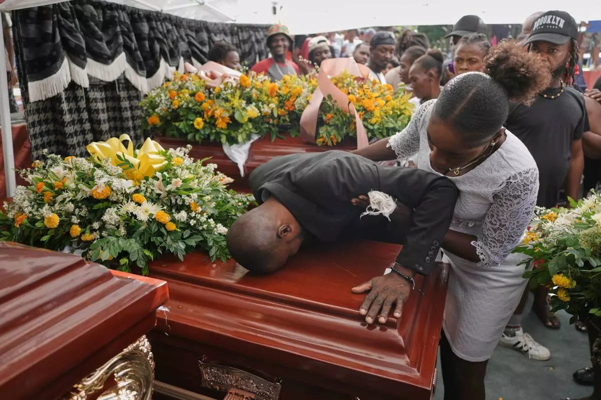 Relatives of Rosiclaire Lenchise mourn during the funeral of victims killed by a landslide triggered by Hurricane Melissa in Petit Goave, Haiti, Saturday, Nov. 15, 2025. (AP Photo/Odelyn Joseph)